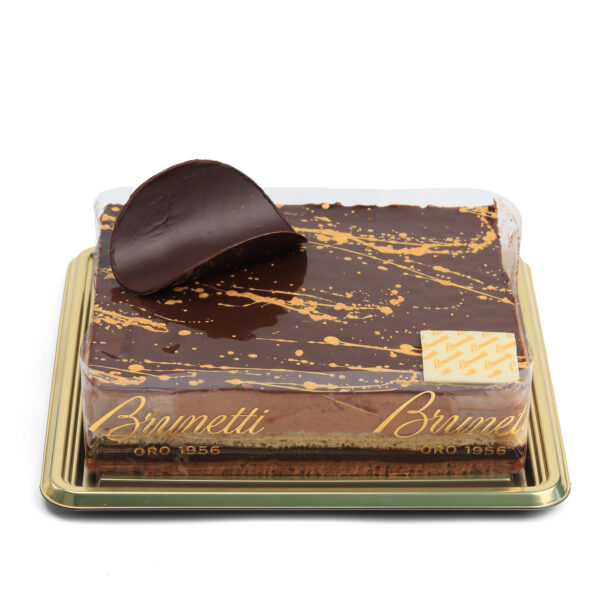 A gourmet chocolate cake with a smooth glaze and decorative topping on a gold tray, labeled "brunetti oro 1956.