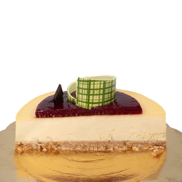 A cheesecake with a glossy red topping and a decorative chocolate piece accompanied by a green checkered chocolate cup.
