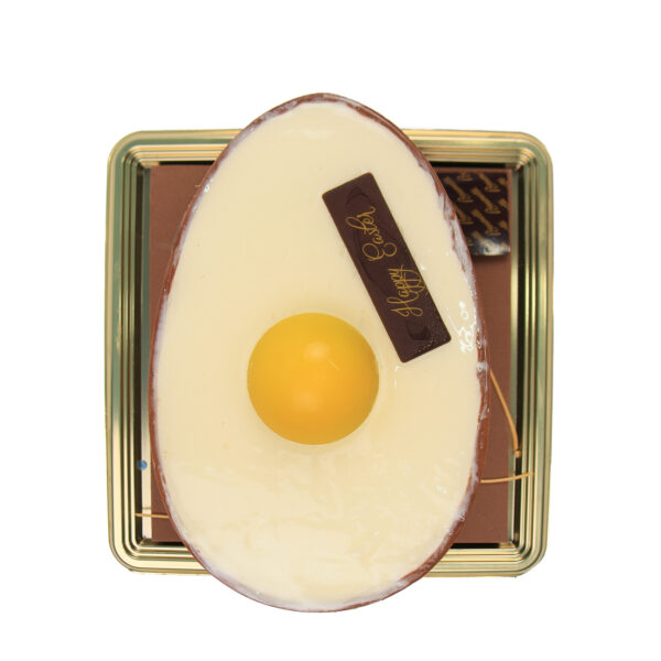 Torta di Pasqua Flat - Cake designed to look like a sunny-side-up egg on a metallic gold tray, featuring a white and brown base and a yellow center.