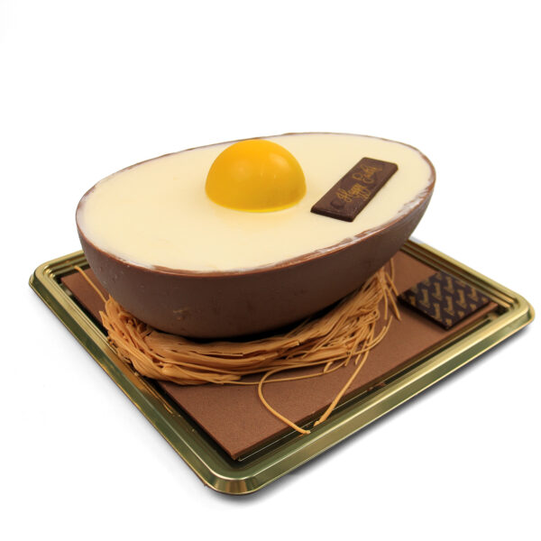 Torta di Pasqua - Cake designed to look like a sunny-side-up egg on a metallic gold tray, featuring a white and brown base and a yellow center.