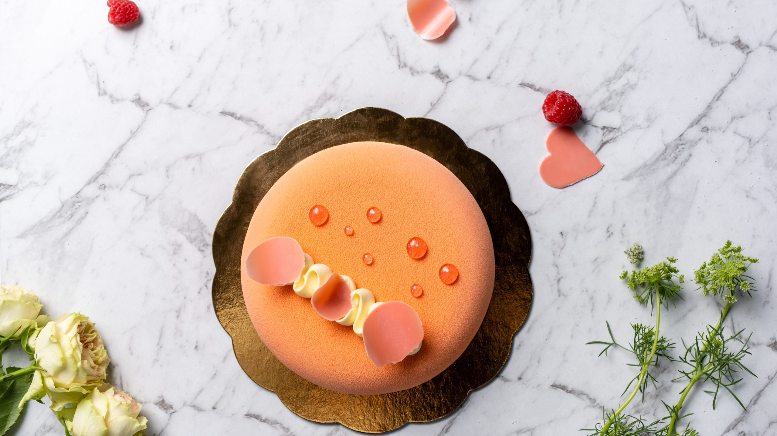 A peach coloured circle cake with rose petals