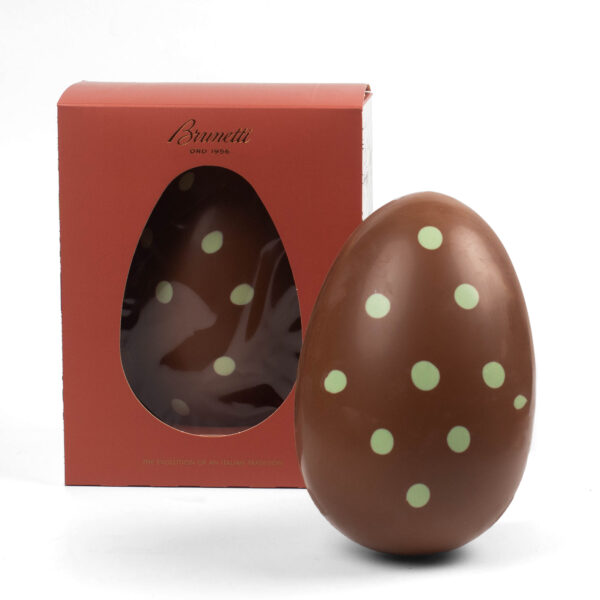 Chocolate easter egg with green polka dots, next to its red packaging box with a transparent window.