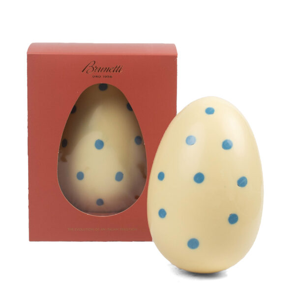 Decorative easter egg with blue dots next to its red packaging with a window displaying the egg inside, labeled "brunetti.