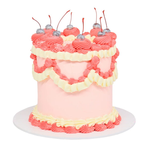 A pink and white cake with cherries on top.