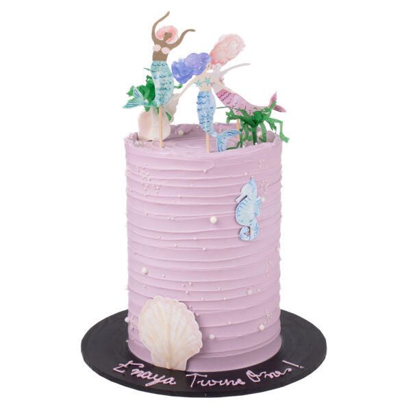 A pastel purple tiered cake adorned with sugar pearls, featuring a seashell motif at the base and topped with two pastel-toned, Mermaid figurine.