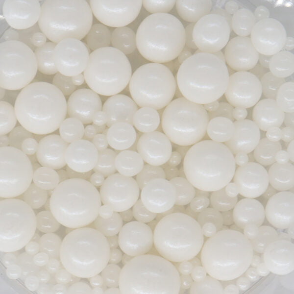 White pearls in a bowl on a white surface.