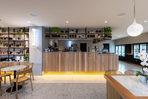 The interior of a coffee shop with wooden tables and chairs.