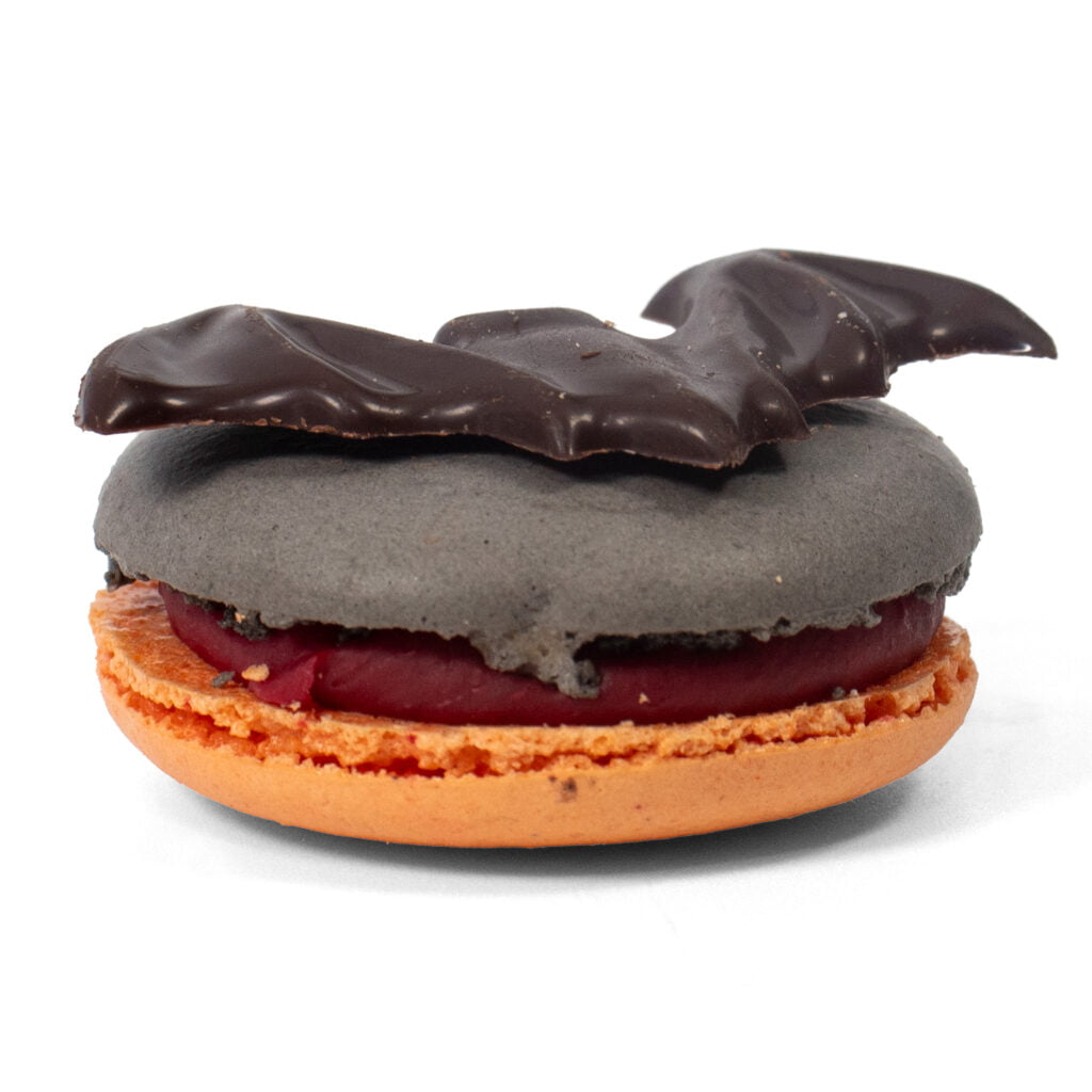 A Sprinkles Halloween bat shaped macaron on top of a white background.