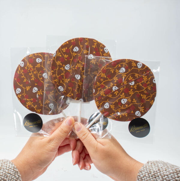 A person holding a Halloween Chocolate-pop with a pattern on it.