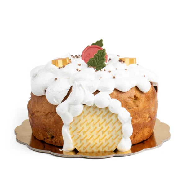 A panettone topped with whipped cream, sprinkles, and decorated with a gold chocolate pieces, isolated on a white background.