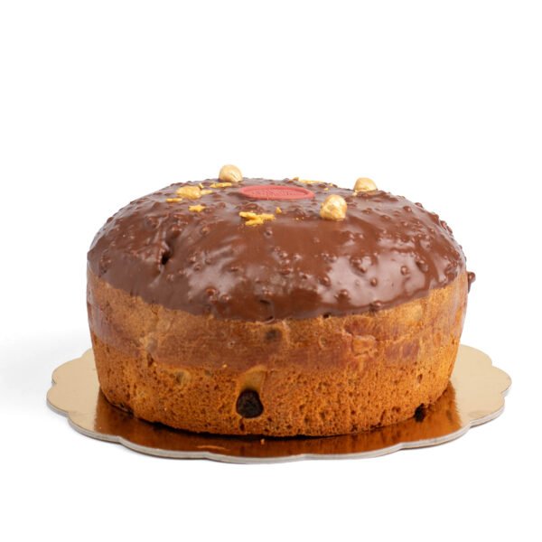 A chocolate-glazed cake decorated with nuts and a single red candy on top, displayed on a round gold board against a white background.