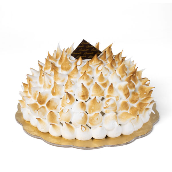 A Bombe Alaska with golden-brown peaks on a golden tray, isolated on a white background.