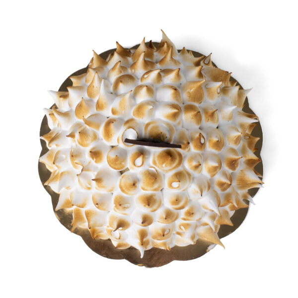 Top view of a Bombe Alaska gelato cake placed on a golden cake board on a white background.