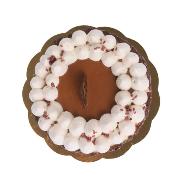 Top view of a round chocolate cake garnished with white cream dollops and sprinkled with dried berries, isolated on a white background.