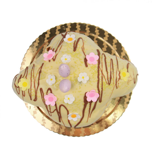 Colomba Con Gelato on a gold doily, featuring white icing drizzled with chocolate, topped with pink, yellow flowers and a purple egg.