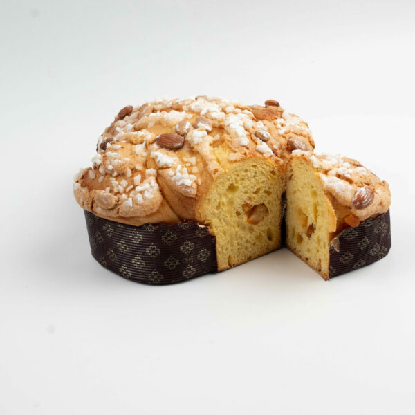 A colomba di pasqua cake with almonds and sugar pearls on top, shown with one slice partially removed, isolated on a white background.